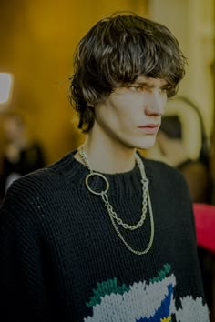 a young man wearing a black sweater with a chain around his neck and necklace on