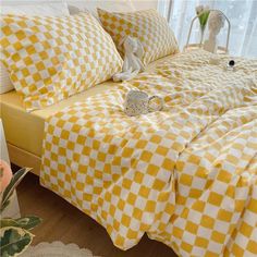 a yellow and white checkered bedspread on a bed with flowers in the corner