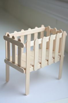 a wooden toy crib sitting on top of a white table next to a wall