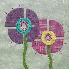 two flowers are shown on the side of a piece of fabric with stitches and thread