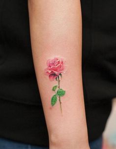 a woman's arm with a pink rose tattoo on the left side of her arm