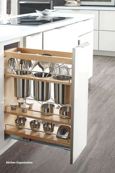 an open cabinet with pots and pans on it in the middle of a kitchen