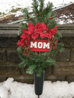 a christmas wreath with poinsettis and pine cones is displayed in a vase