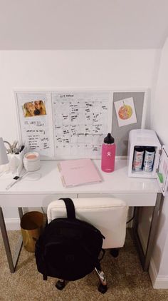 a white desk with a black backpack on top of it and a pink cup next to it