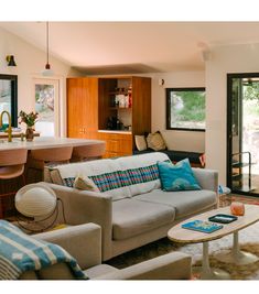 a living room filled with furniture next to a kitchen and dining room table in front of a sliding glass door