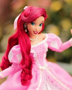 a barbie doll with long red hair wearing a pink dress and tiara holding her hand out