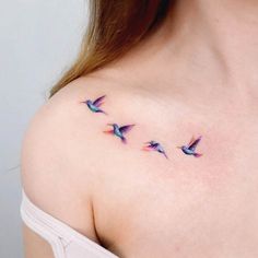 a woman's shoulder with three small birds on the left side of her chest