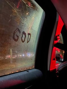 the word god is written on the window of a car in front of a red light