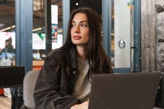 a woman sitting at a table with a laptop in front of her - stock photo - images