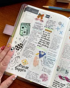 a woman's hand holding an open bible with stickers on it and writing in the pages