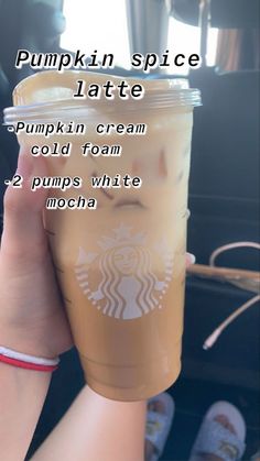 a person holding up a cup of pumpkin spice latte with information about the drink