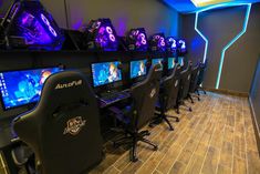 a gaming room with several computer monitors and video game controllers on the wall, along with chairs