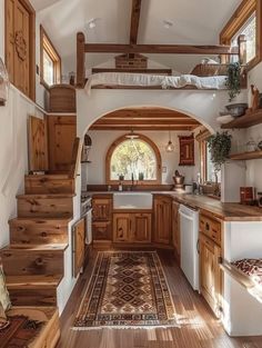 a kitchen with wooden cabinets and stairs leading up to the upper floor, along with an area rug on the hardwood flooring