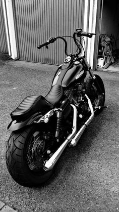 a black and white photo of a motorcycle parked in front of a garage with the door open