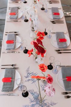 a long table is set with place settings and flowers in vases on each side