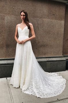 a woman in a wedding dress standing on the sidewalk