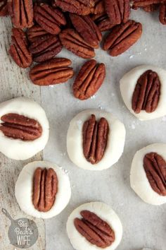 some pecans sitting on top of a table next to white frosted doughnuts