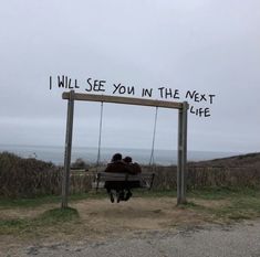 two people sitting on a bench under a sign that says i will see you in the next life