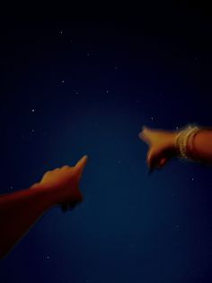 two hands reaching towards each other in the dark sky at night with stars behind them