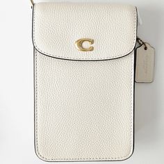 Coach Phone Crossbody Bag Color: Brass/Chalk Product Details Materials : Polished Pebble Leather Fabric Lining Strap : Detachable Strap With 21.5" Drop For Shoulder Or Crossbody Wear Features : Outside Open Pocket Two Credit Card Slots Snap Closure Measurements : Length: 4.5" Height: 7.25" Width: 1.0" Fits All Phone Sizes Up To An Iphone X And Samsung S7 Edge Comes From A Non-Smoking Home. Please Note That The Measurements Of The Item Will Be Approximate Sizes. Color Of The Item Might Be Slightl White Rectangular Shoulder Bag With Cell Phone Pocket, White Phone Shoulder Bag For On-the-go, White Shoulder Phone Bag For On-the-go, White Luxury Shoulder Bag With Mobile Phone Holder, White Everyday Use Phone Pouch Bag, White On-the-go Shoulder Phone Bag, White Leather Phone Bag With Removable Pouch, White Crossbody Phone Bag For On-the-go, White Rectangular Phone Bag With Cell Phone Pocket