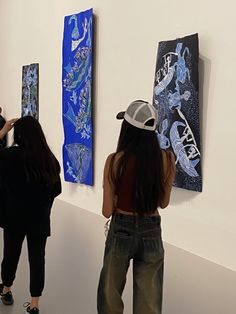 two women are looking at artwork on the wall