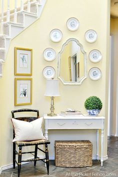 a room with yellow walls and pictures on the wall, including a white console table