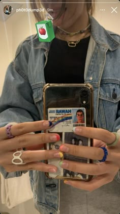 the woman is holding her cell phone with both hands and wearing rings on each hand