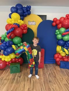 a young boy standing in front of a bunch of balloons