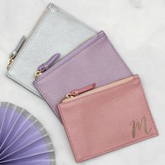 two small purses sitting on top of a table next to a purple and white fan