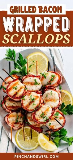 grilled bacon wrapped scallops on a plate with lemons and parsley