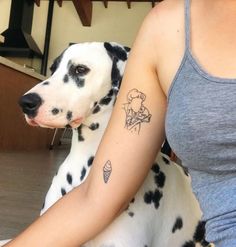 a dalmatian dog sitting next to a woman with a tattoo on her arm