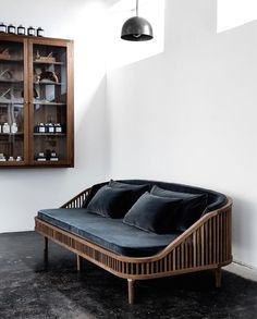 a wooden couch with black pillows on it