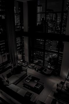 a black and white photo of a living room with city lights in the background at night