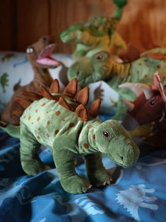 stuffed dinosaurs are lined up on a bed