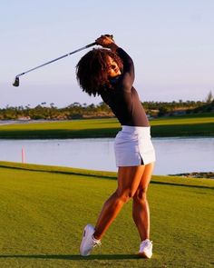 a woman is swinging her golf club on the course