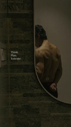 a man standing in front of a mirror with his back turned to the camera, looking at himself