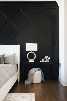 a black and white bedroom with wood flooring, wall paneling and bedding