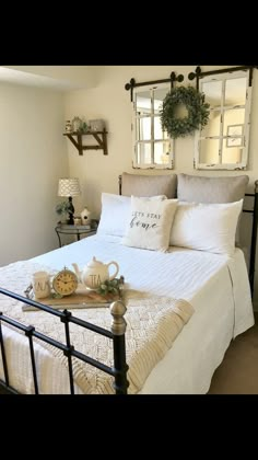 a bed with white linens and pillows in a bedroom next to a wall mounted mirror