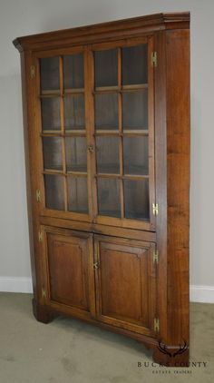 an old wooden bookcase with glass doors on the front and bottom shelves, in a room