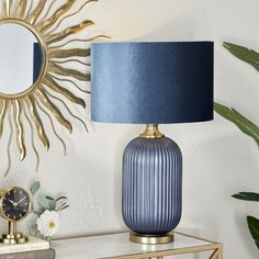 a blue lamp sitting on top of a table next to a mirror and a clock