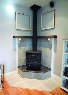 an old fashioned stove in a room with wood flooring and two framed pictures on the wall