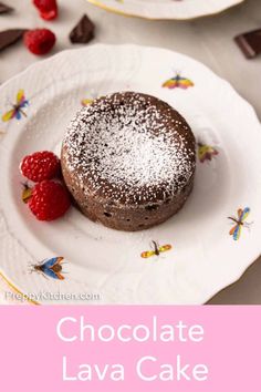 chocolate lava cake on a white plate with raspberries and chocolate chips in the background