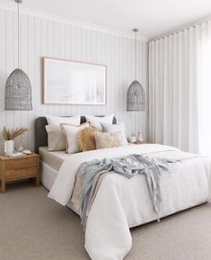 a white bed sitting in a bedroom next to two lamps on either side of the bed