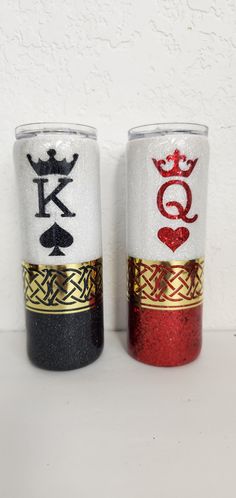 two cups with different designs on them sitting next to each other in front of a white wall