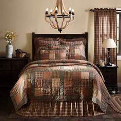 a bedroom with a chandelier and bedding in brown tones, including plaid