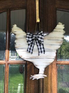 a white chicken hanging from the side of a door with a black and white bow on it's head