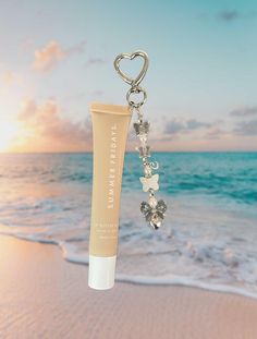 a tube of sunscreen is hanging from a keychain on the beach at sunset