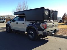 a truck with a camper attached to it's bed parked in a parking lot