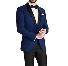 a man in a blue tuxedo poses for a photo with his hands in his pockets