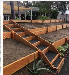 an outdoor garden with wooden steps and plants in the dirt near a house on a beach